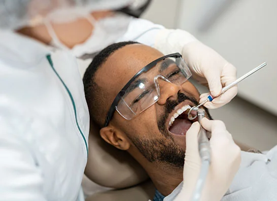 A dentist performing a routine dental check-up on a patient wearing protective glasses in a clinic setting - Composite Filling in Bakersfield, CA