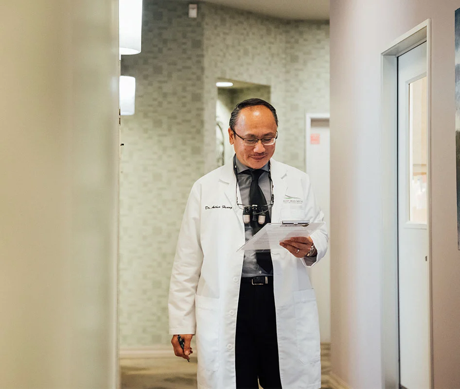 Dr. Huang smiling and looking at clipboard - Dentist in Bakersfield, CA