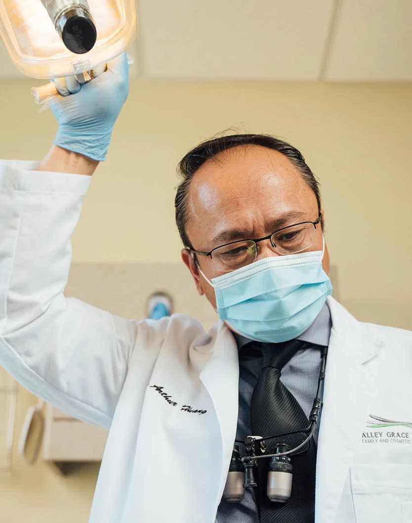 Dr Huang holding his overhead light while wearing a mask and surgeon coat - Porcelain Inlays and Onlays in Bakersfield, CA